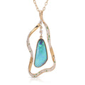 A gold pendant necklace featuring a teardrop-shaped iridescent blue-green opal stone, surrounded by an abstract wavy gold frame paved with small clear stones and accented with green stones, shown on a white background.
