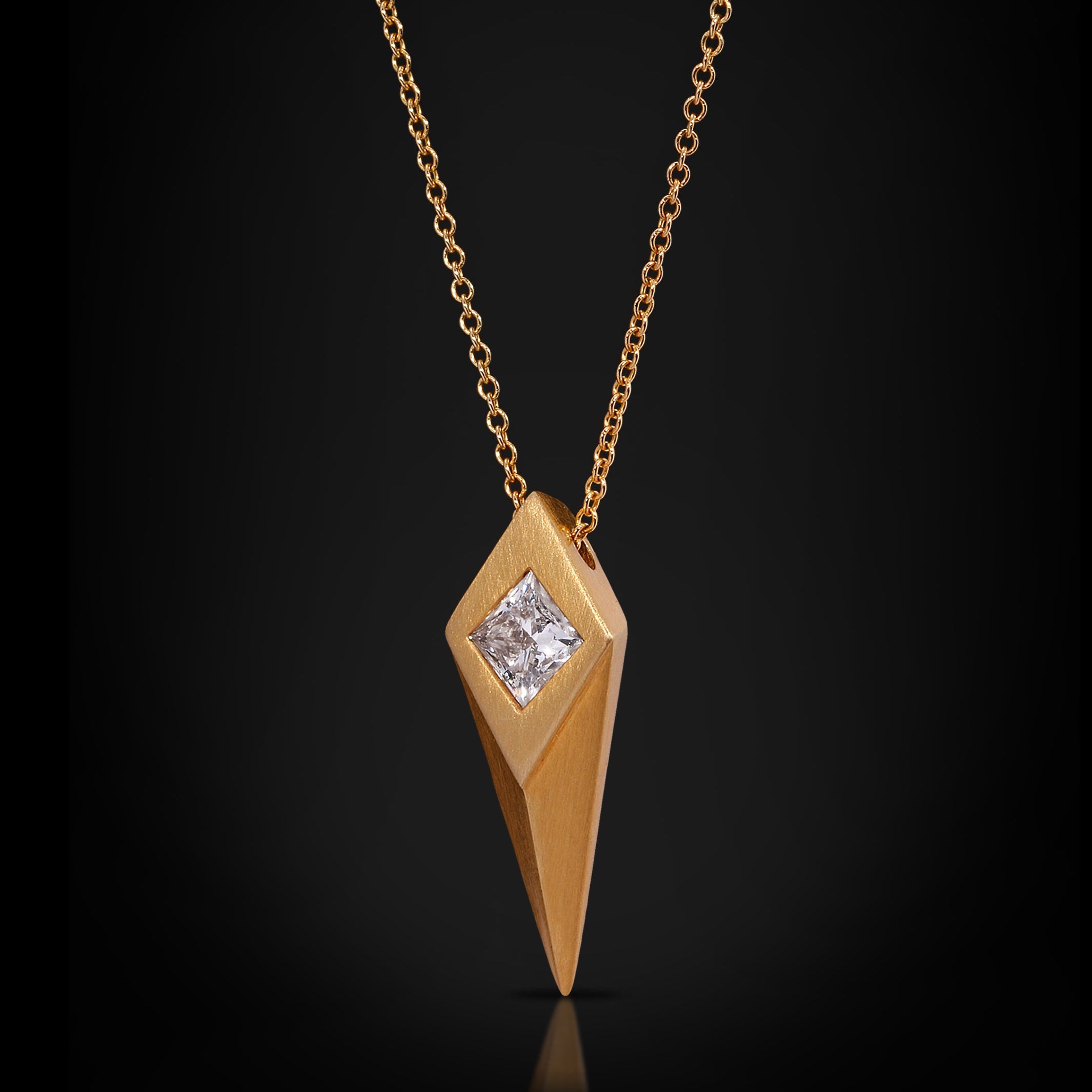 Gold necklace with a diamond pendant on a black background