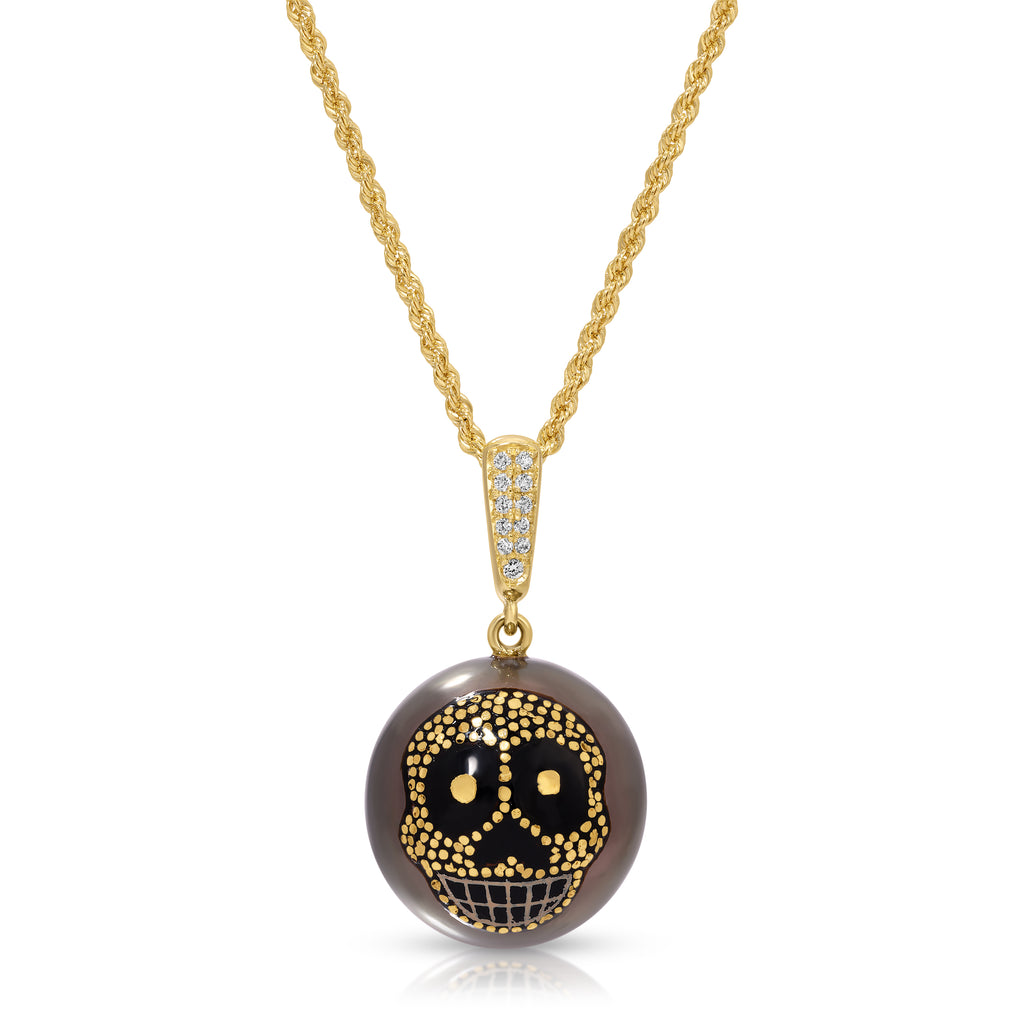 A gold chain necklace with a round pendant featuring a black and gold sugar skull design on a smoky brown background, set against a plain white background.