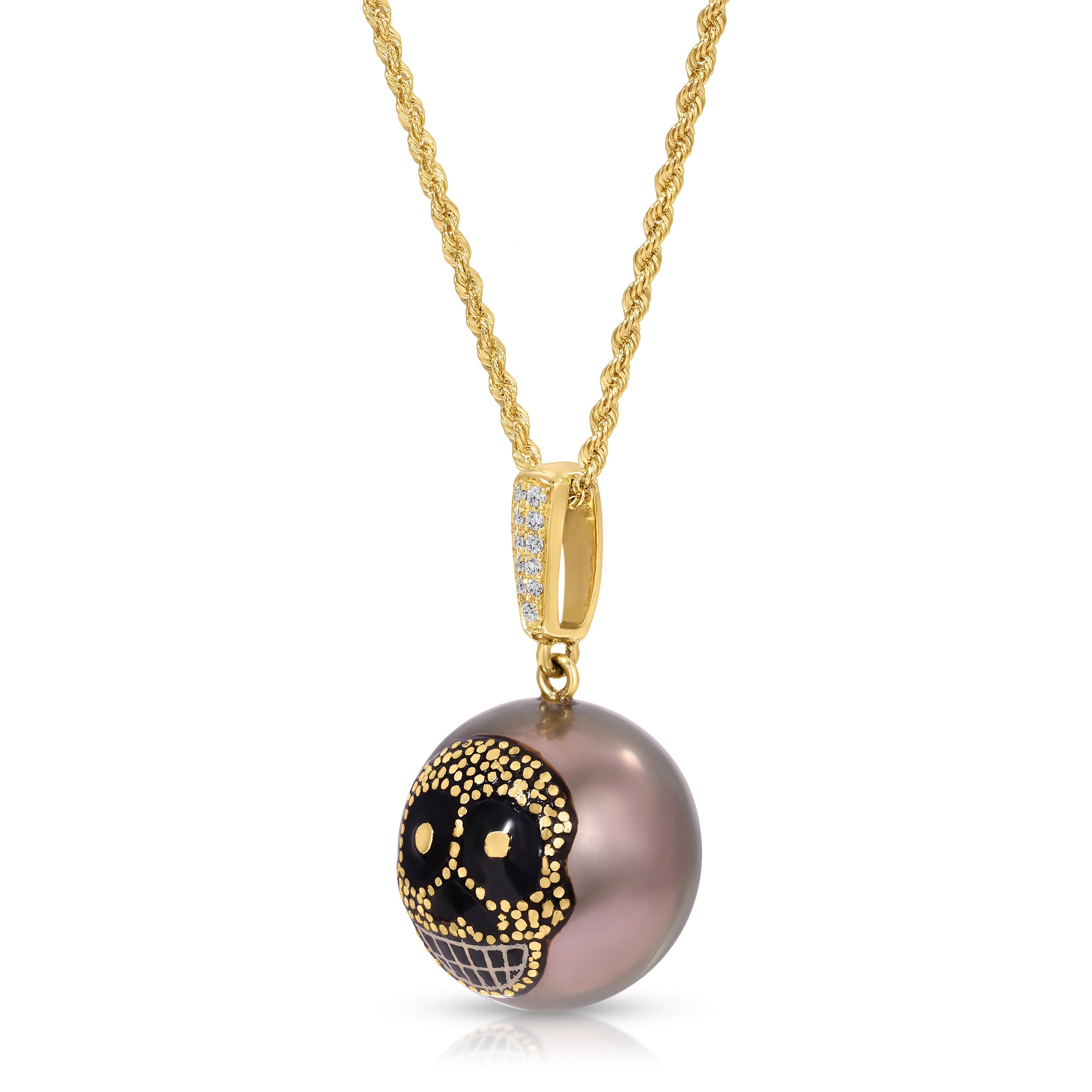 A gold chain necklace with a round pendant featuring a black and gold sugar skull design over a dusty purple-gray pearl, shown on a white background.